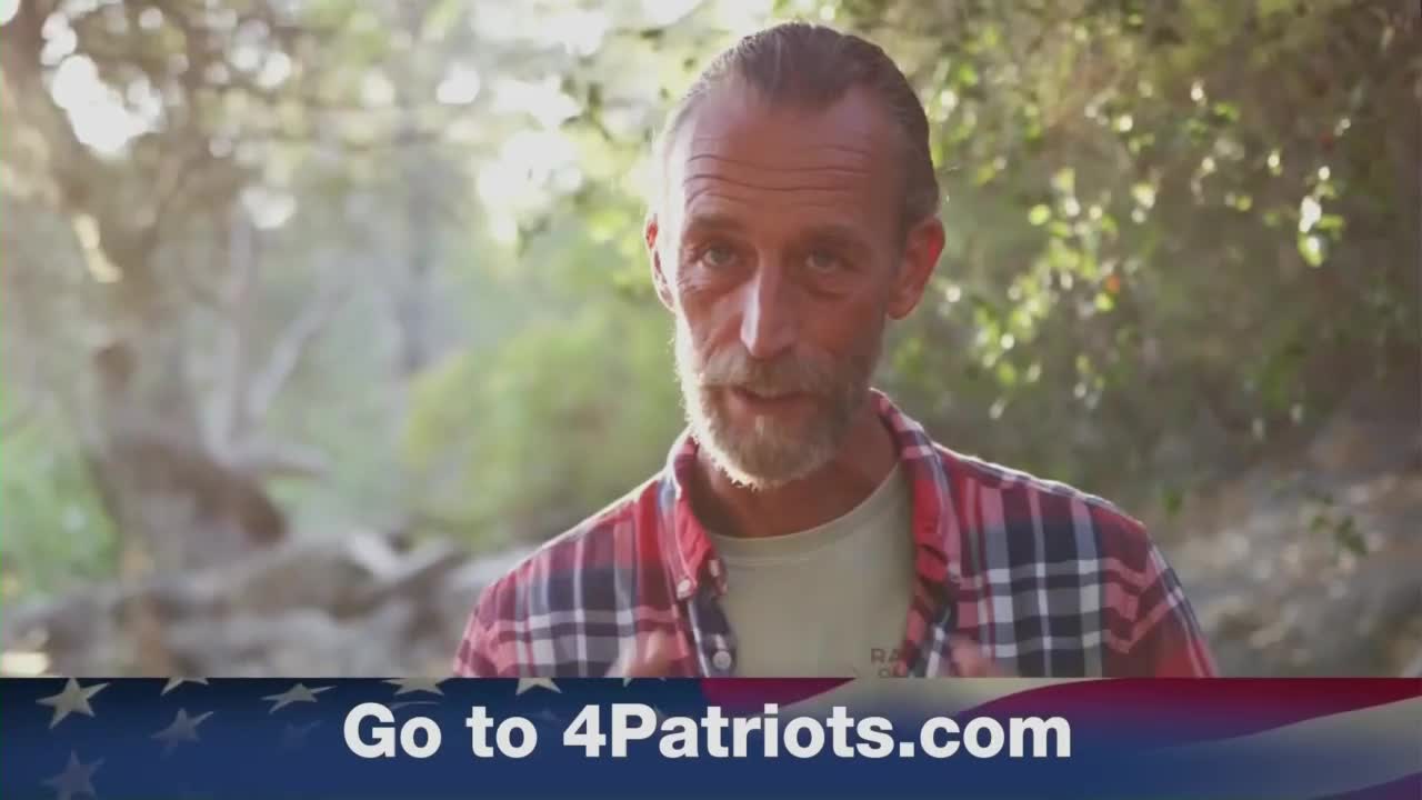A man in a plaid shirt speaks directly to the camera, framed by a blurred outdoor background. Below him, a banner with the website "Go to 4Patriots.com" appears, typical of ads on One America News Network.
