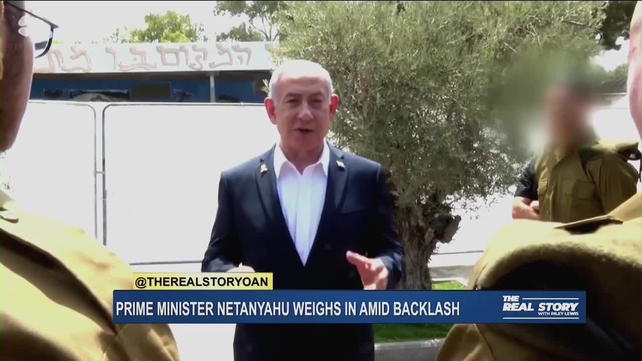 Prime Minister Netanyahu is speaking, flanked by soldiers, with a building in the background. The lower third of the screen identifies the segment as "The Real Story" on One America News Network.
