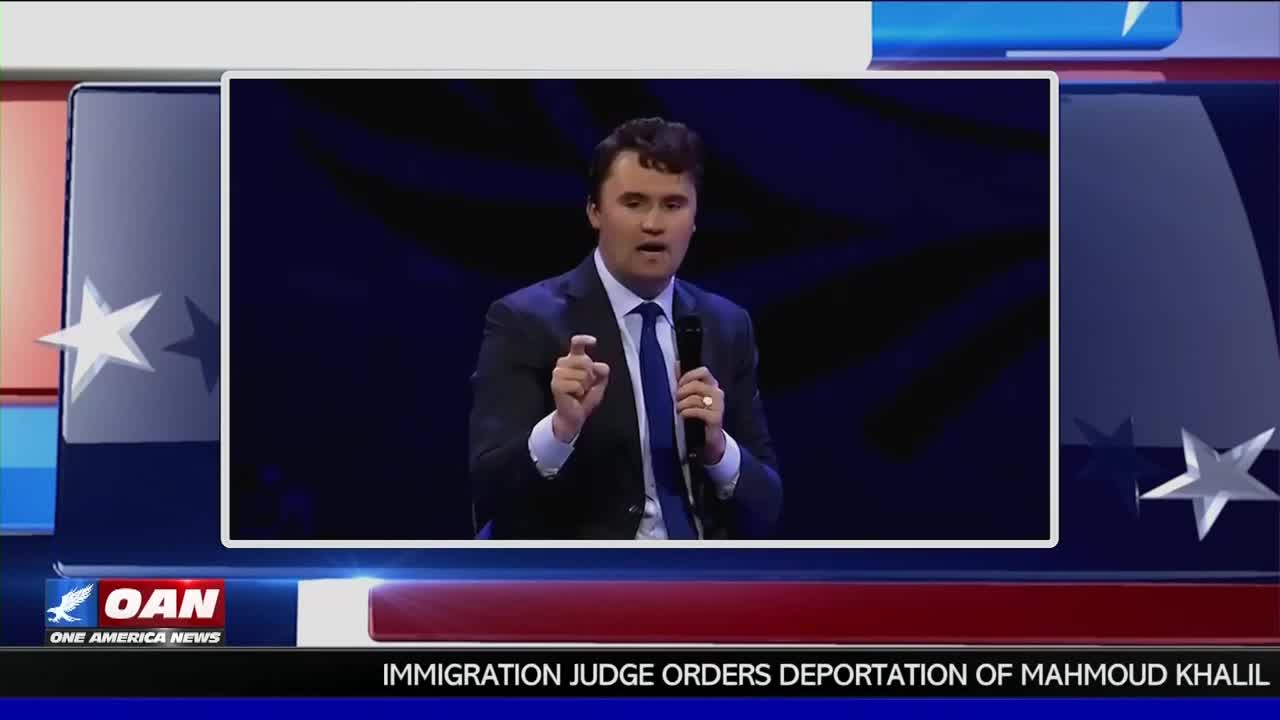 On the screen, a man in a suit gestures with his right hand, holding a microphone in his left. The One America News Network logo is visible in the corner, and a headline about deportation is displayed.

