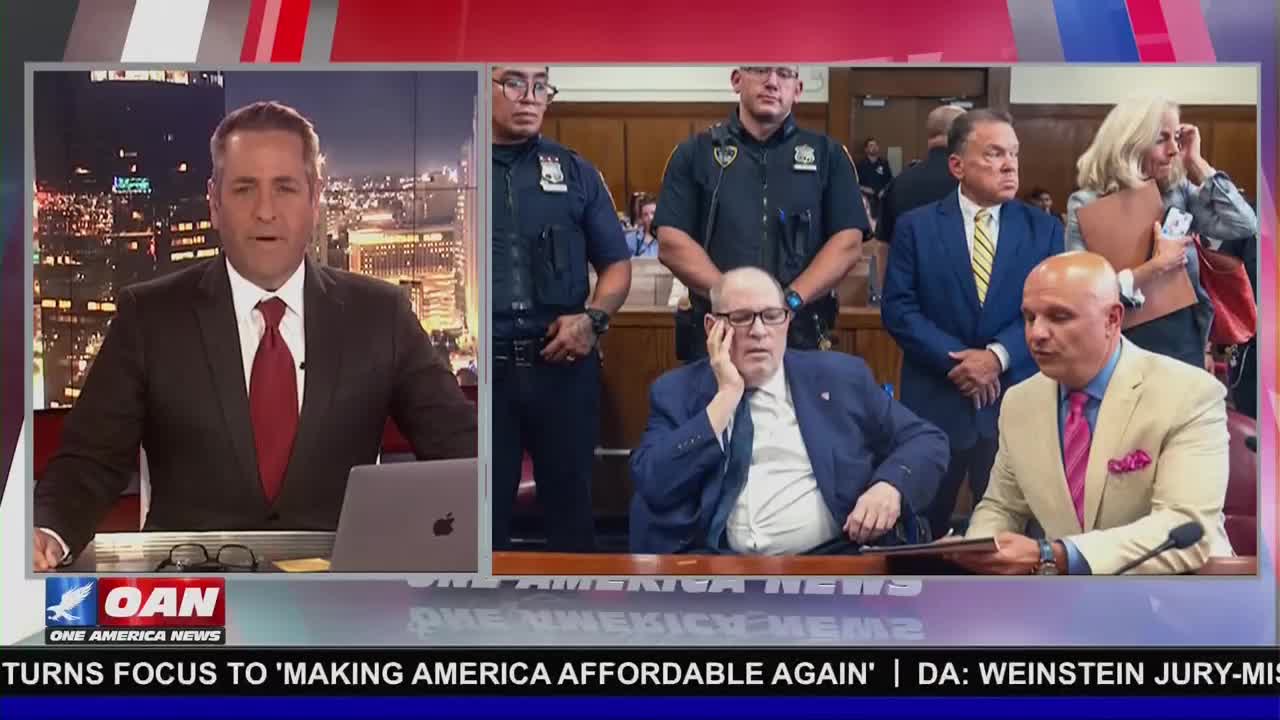 A news anchor on One America News is reporting, while a courtroom scene plays on the screen behind him. The broadcast shows a man in a blue suit, sitting and resting his head on his hand, with police officers standing guard.
