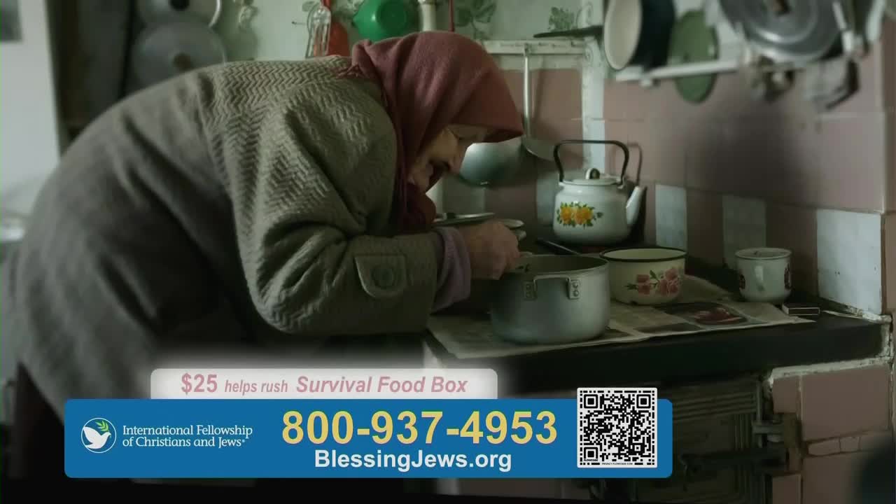 An older woman, wearing a headscarf, leans over a pot on a stove, stirring something inside. The scene, broadcast on One America News Network in the United States, is meant to solicit donations for "Survival Food Boxes."
