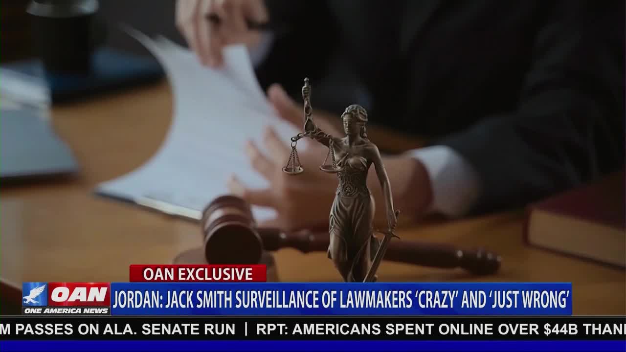 A small statue of Lady Justice stands on a table, balanced in front of a gavel and a person handling papers. The lower third of the screen, from One America News Network, announces a story about Jack Smith.
