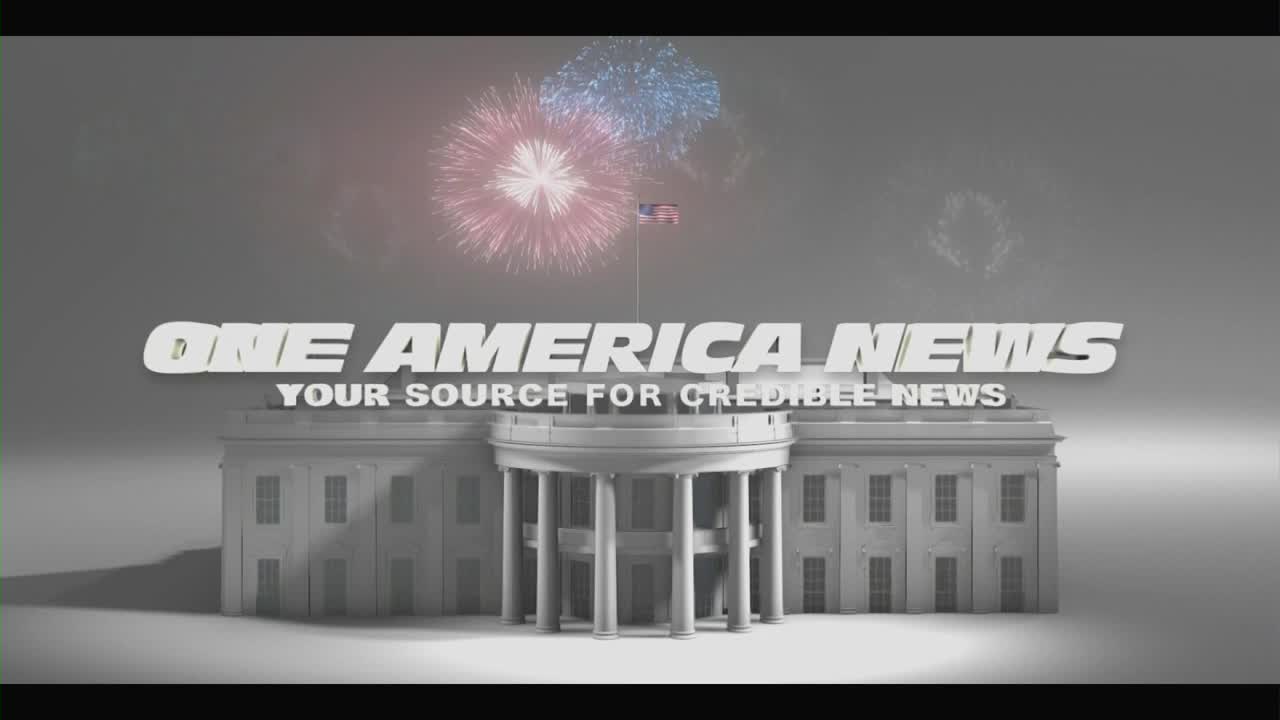 The White House, rendered in grayscale, sits below the "One America News" logo. Fireworks burst in the sky above the building, and the American flag flies from the roof.
