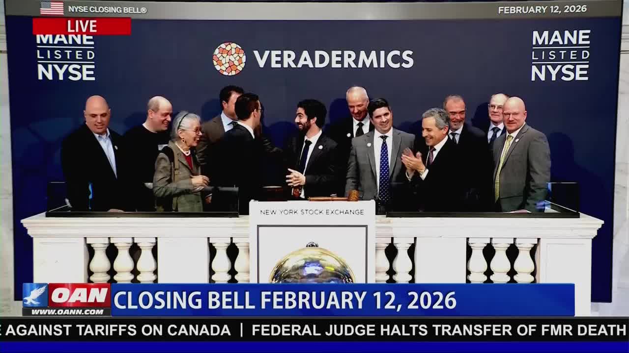 A group of people stands on the New York Stock Exchange floor, some shaking hands and others clapping. The Veradermics logo hangs behind them, as the OAN broadcast announces the closing bell for February 12, 2026.