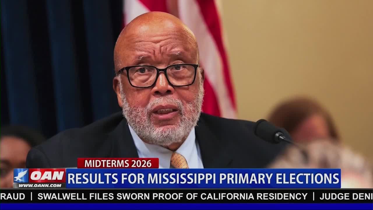 A man with glasses and a beard speaks into a microphone. A banner below him reads "OAN RESULTS FOR MISSISSIPPI PRIMARY ELECTIONS."
