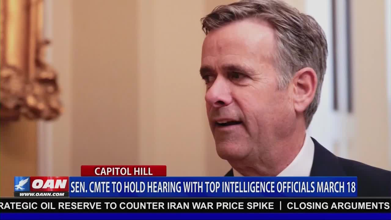 A man in a suit speaks, his expression serious. Below him, a chyron announces a Senate committee hearing with intelligence officials.