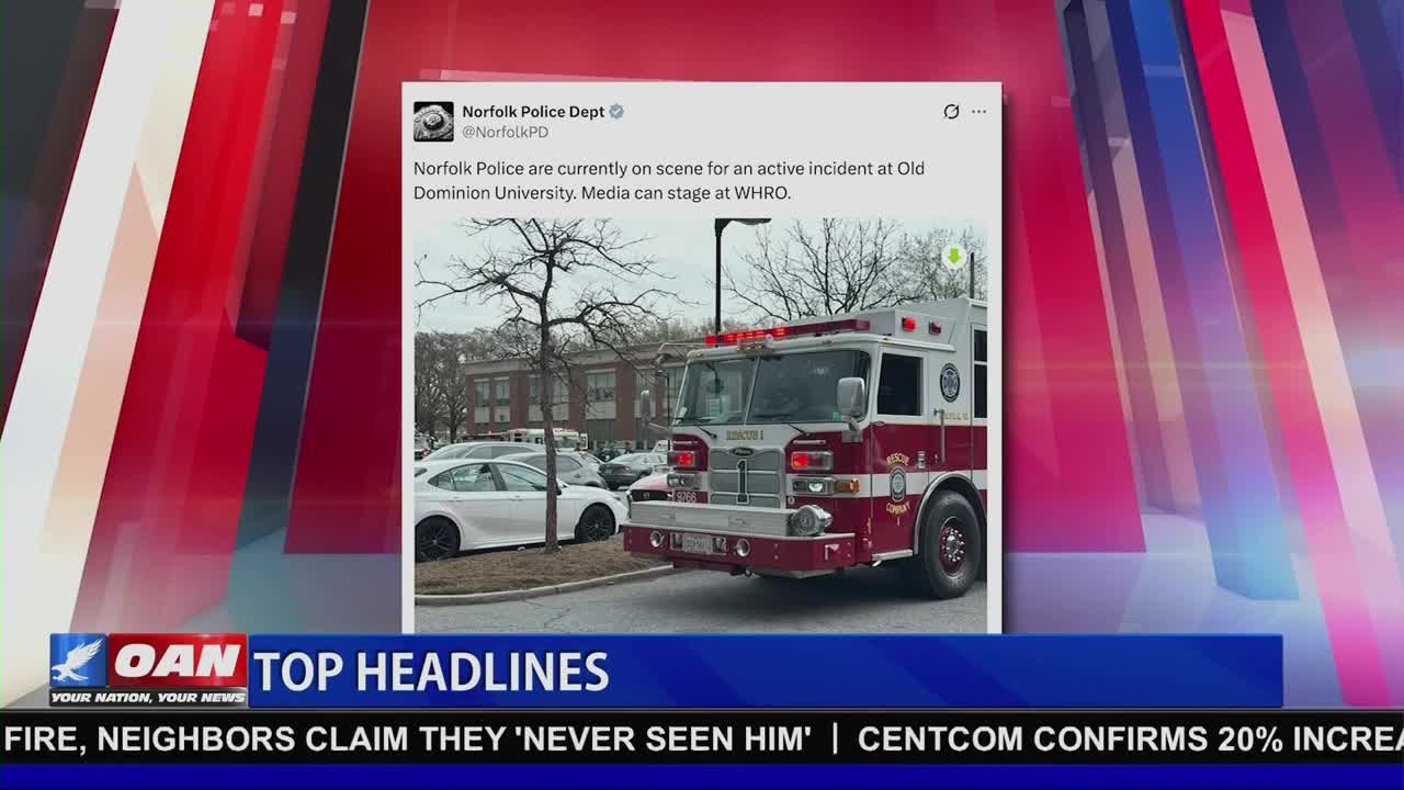 A large red and white fire truck sits parked on a street. The truck's emergency lights are flashing.