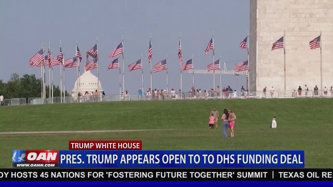 American flags snap in the breeze before the Washington Monument. A few families stroll across the green lawn, enjoying the day.