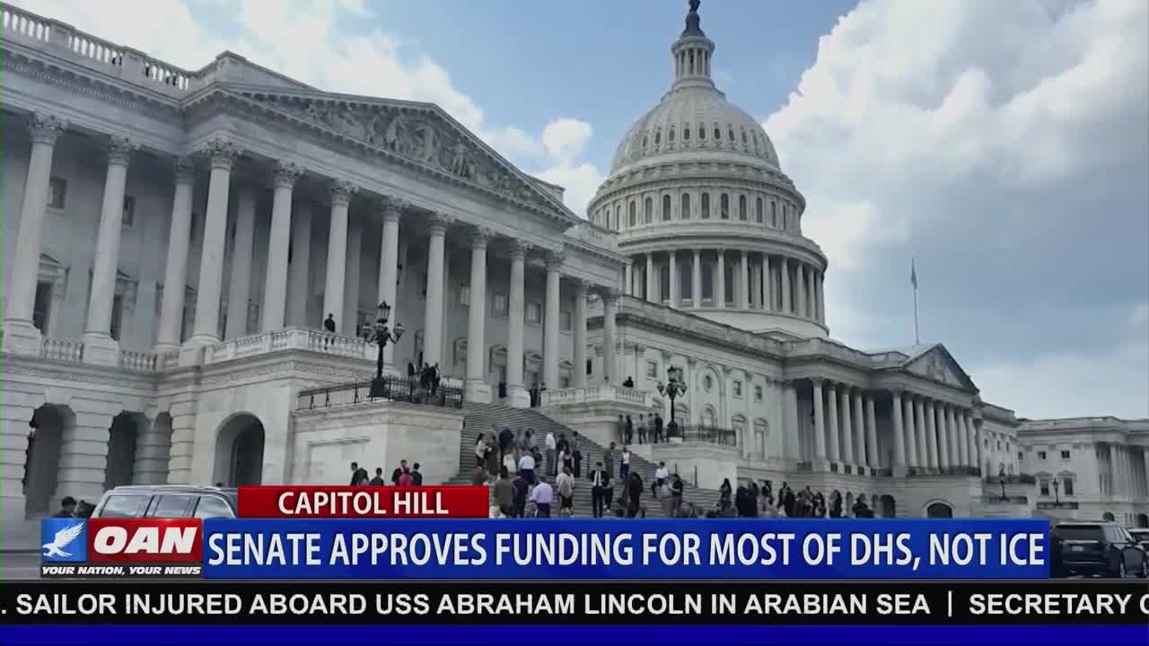 People walk up the steps of the Capitol Building under a bright sky. A dark sedan pulls away from the curb in front of the building.