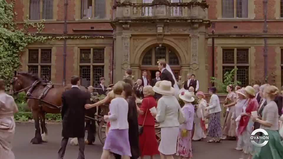 The newly married couple emerges from the ornate building, followed by their wedding party. A horse-drawn carriage waits, ready to carry them away as guests line the path.
