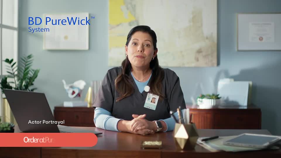 A woman in scrubs sits behind a desk, looking directly at the camera. The "BD PureWick System" logo is visible in the upper left corner, and a banner at the bottom reads "Order at Pur."
