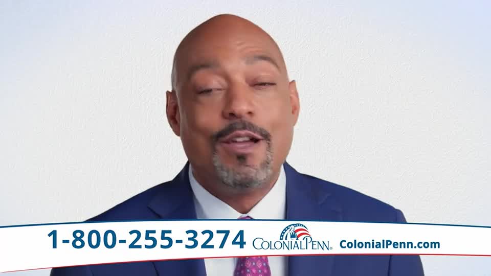 A man in a blue suit is speaking, his mouth open, and his eyes are closed. Underneath him, a phone number and the Colonial Penn logo are displayed.

