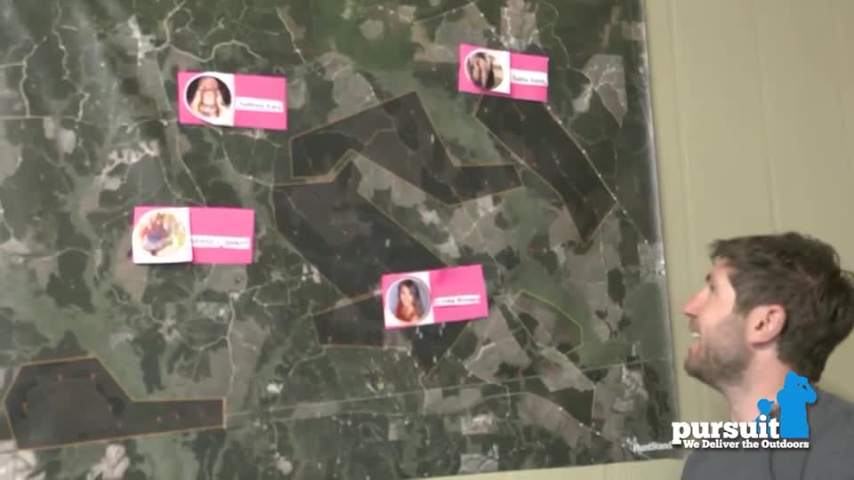A man smiles, looking up at a map of land with photos and names attached. The Pursuit Channel logo is visible in the bottom right corner.
