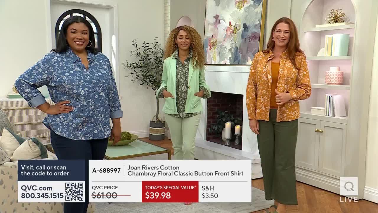 Three women stand on a QVC set in the United States, each modeling a different floral shirt. The on-screen graphics display the item's name and price, along with a QR code for easy ordering.
