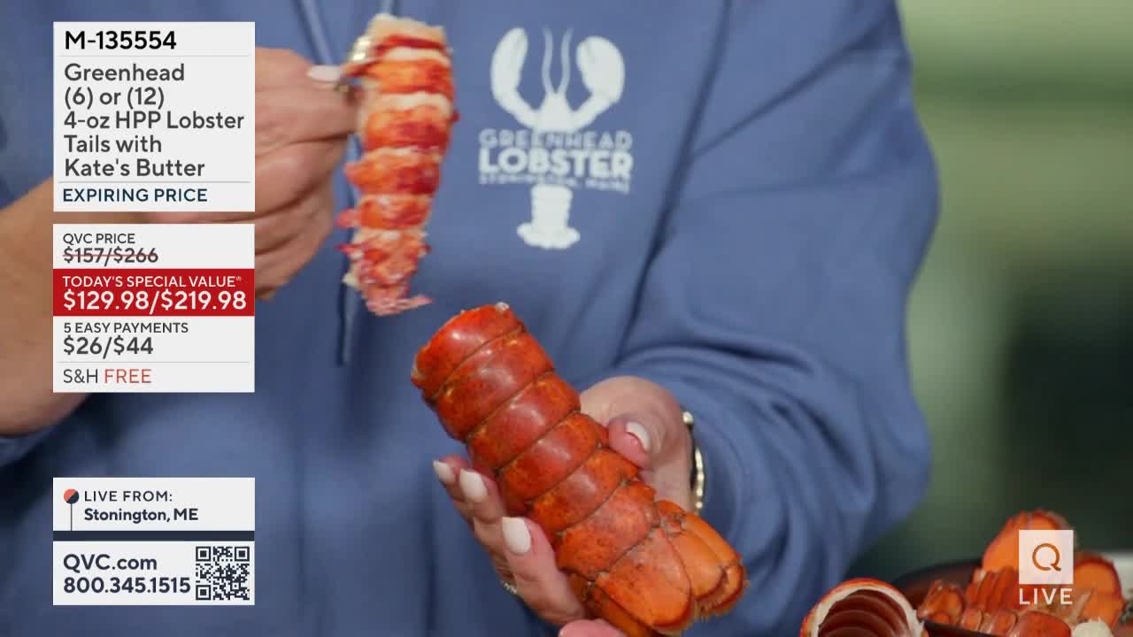 A person holds two cooked lobster tails, one in each hand, showcasing them for a QVC segment. The lobster meat is a vibrant red, and the presentation highlights the product's appeal.
