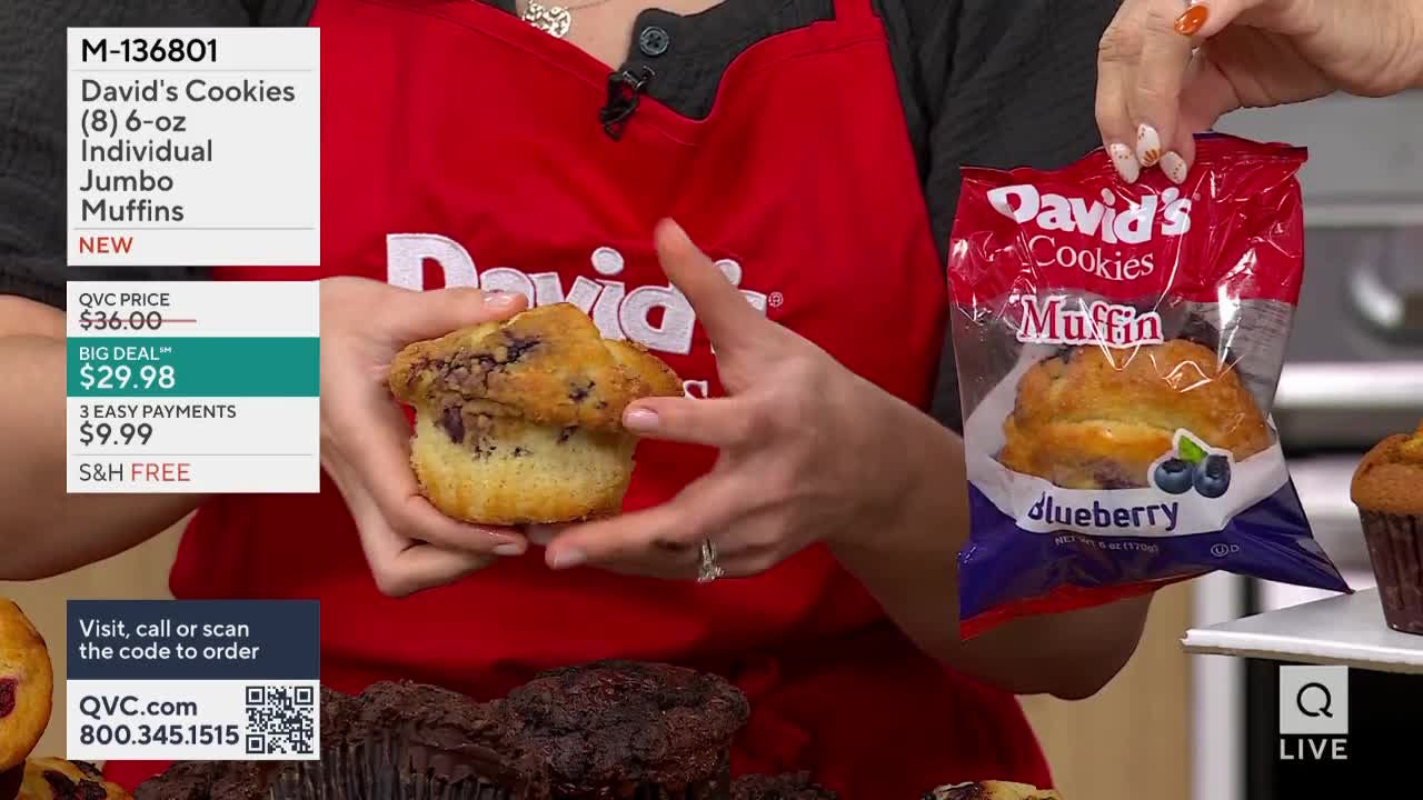 A woman in a red apron holds a large blueberry muffin, displaying it for the camera. Beside her, another hand presents a sealed bag of the same muffins, the "David's Cookies" logo clearly visible.
