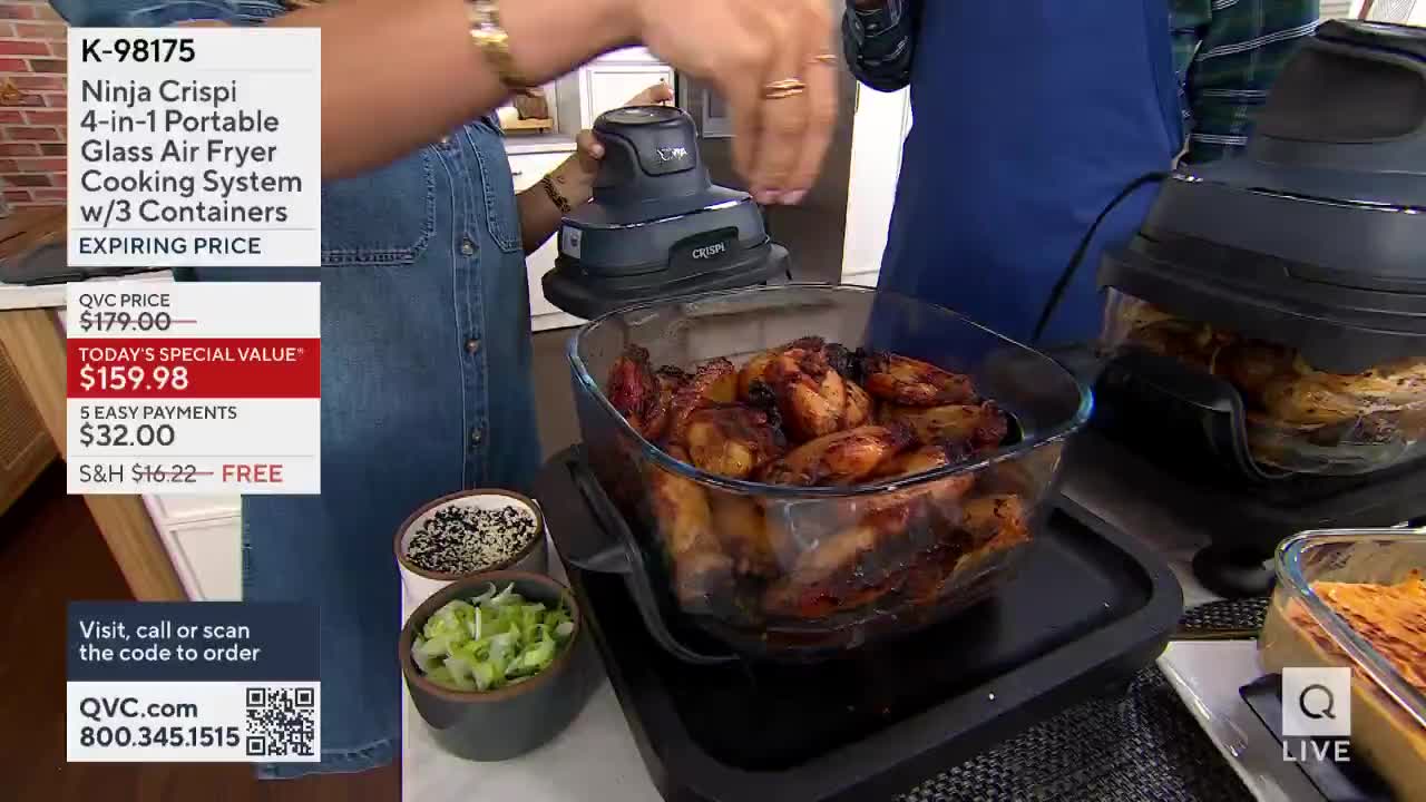 A woman in a denim dress is lifting a lid off a glass dish filled with chicken wings. The QVC set features a cooking system and various side dishes.
