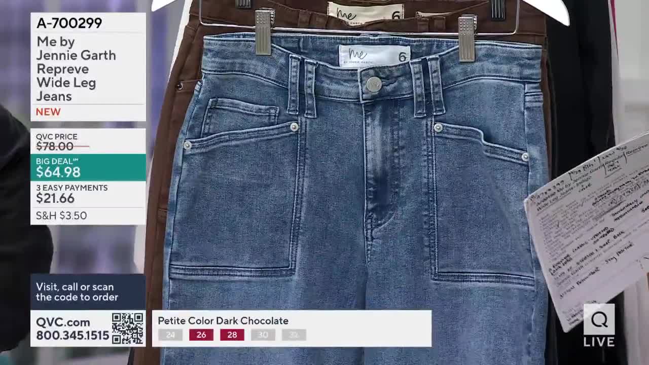 A pair of blue denim jeans hangs on a rack, centered in the frame. Next to it, a brown pair is partially visible, and a handwritten note is held nearby.
