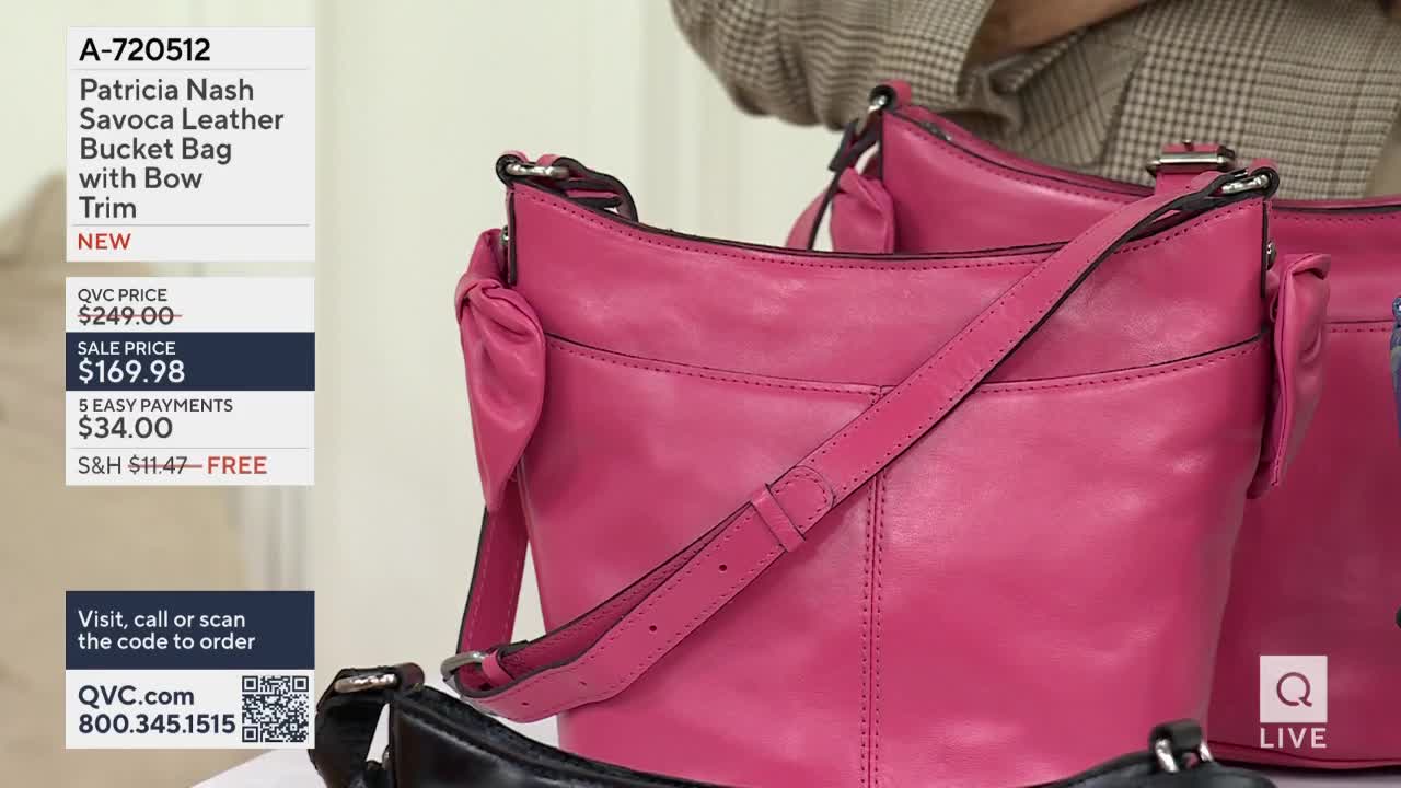 A bright pink leather bucket bag with a bow detail sits on display. Another bag, partially visible, is a deep blue.