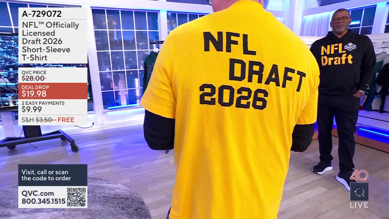 A man stands in a bright yellow t-shirt with "NFL DRAFT 2026" printed in large black letters across his back. Another man in a black hoodie with "NFL Draft" on it stands to his right.