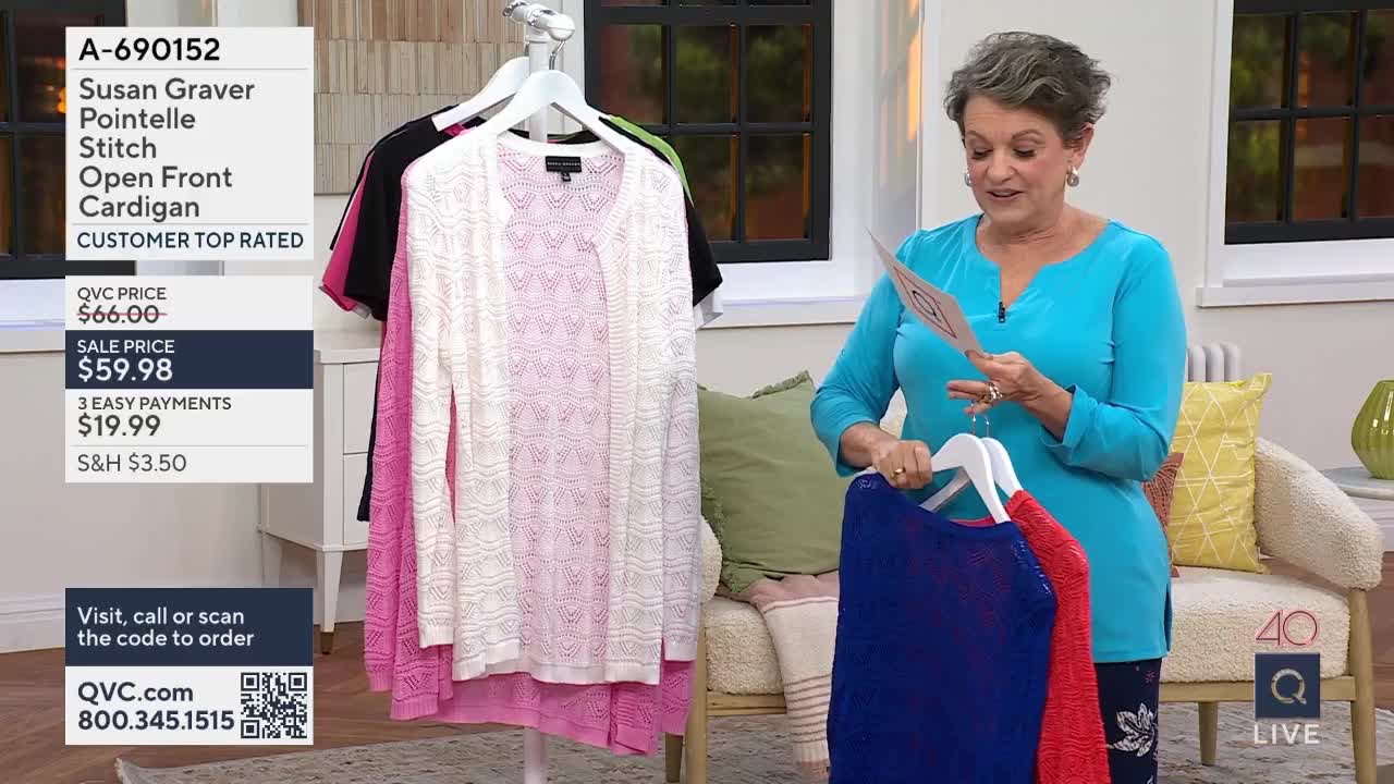 A woman in a bright blue top holds up a card and two sweaters, one royal blue and one red. Behind her, a rack displays several open-front cardigans in pink and white.