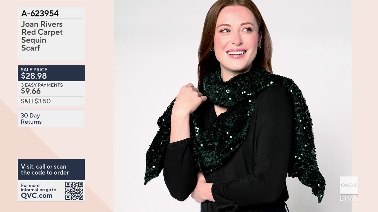 A woman on QVC2 models a dark green scarf, its surface covered in sparkling sequins. She smiles, holding the scarf up as if showing off its texture.
