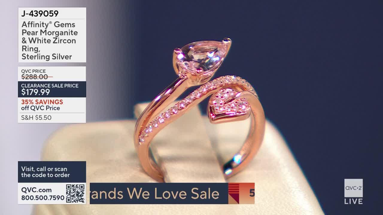 A pear-shaped morganite stone tops a rose-gold ring on display for a QVC2 "Brands We Love Sale." The ring's band curves around a small heart-shaped cluster of white zircon stones.
