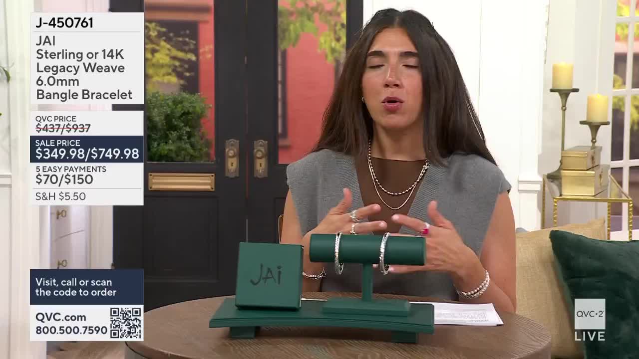 A woman on QVC2 gestures towards two bangle bracelets displayed on a green stand. The on-screen graphics highlight the price and details of the jewelry.
