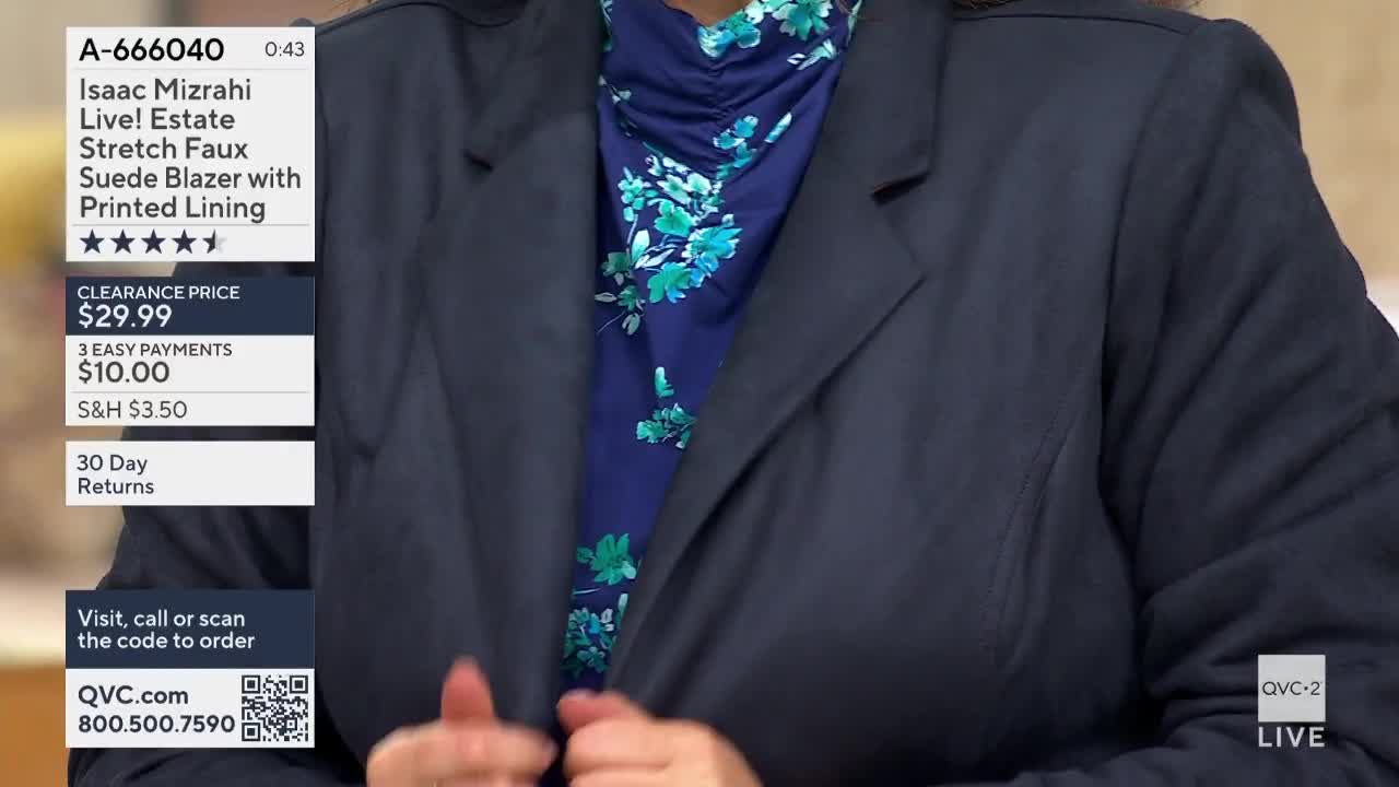 A woman in a navy blazer is adjusting the lapels, revealing a floral-print top underneath. The QVC2 logo is visible in the corner, and a price tag for an Isaac Mizrahi blazer is displayed on the left.
