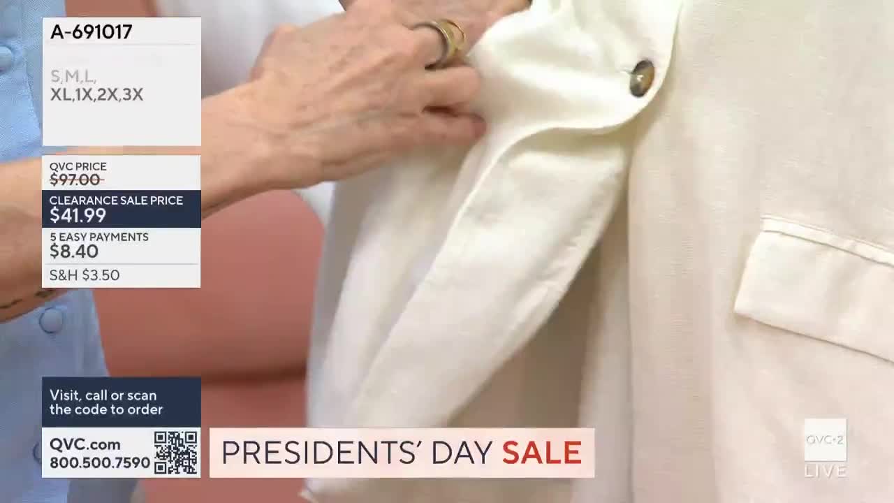 A hand adjusts the lapel of a cream-colored blazer. The QVC2 Presidents' Day Sale is advertised on screen.