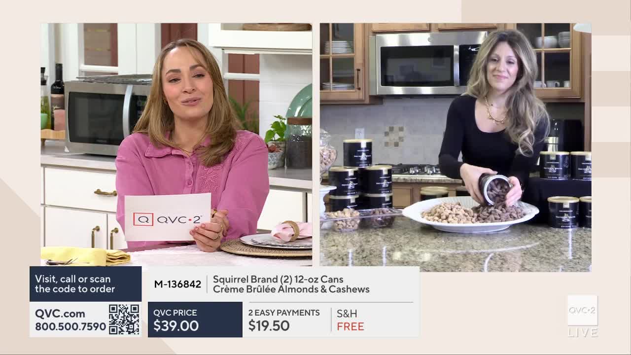 A woman on QVC2 is pouring nuts from a dark can onto a large white platter. Another woman, also on screen, holds up a card with the QVC2 logo.