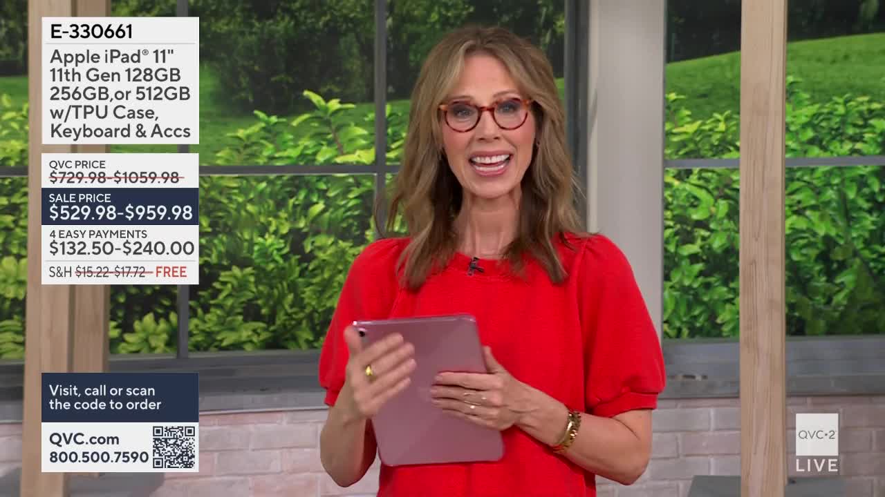 A woman in a bright red top smiles, holding up a rose-gold iPad. The QVC2 logo flashes in the corner as she presents the device.