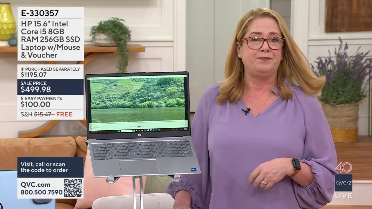 A woman in a lavender blouse stands next to an HP laptop displaying a scenic view. The QVC2 logo is visible in the lower right corner.
