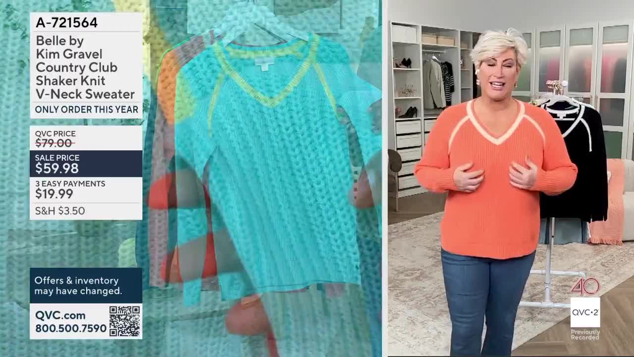 A woman on QVC2 holds up an orange sweater, her hands framing the V-neck. Beside her, a teal sweater hangs, its textured knit clearly visible.