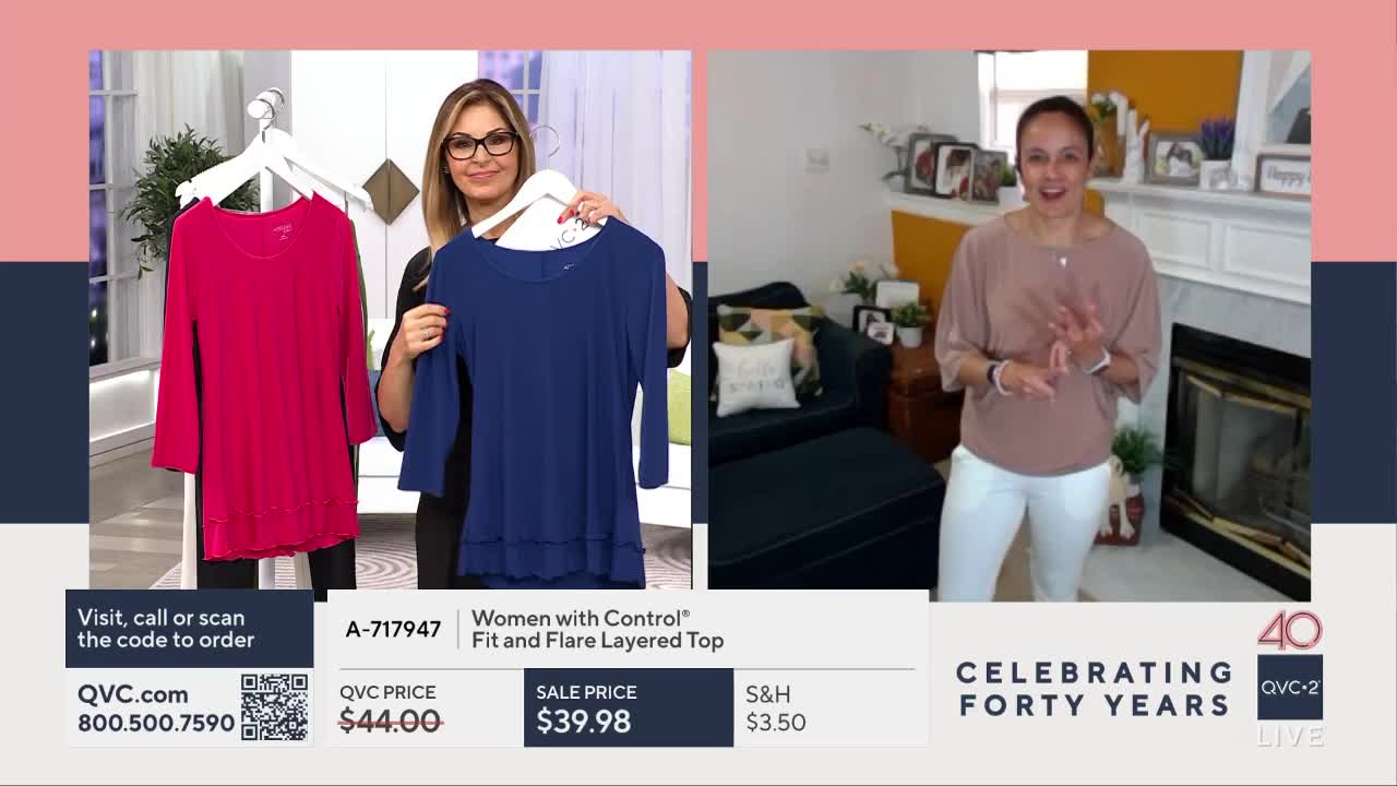 A woman holds up a blue, layered top on a hanger, while another woman in a taupe shirt and white pants gestures enthusiastically. The QVC2 logo and a "Celebrating Forty Years" banner appear at the bottom.