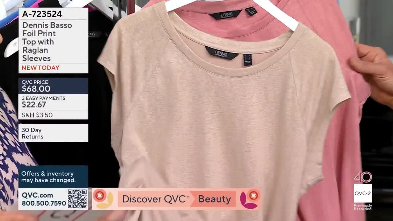 A hand adjusts a tan t-shirt hanging on a rack, revealing a pink one behind it. The QVC2 logo appears on screen.