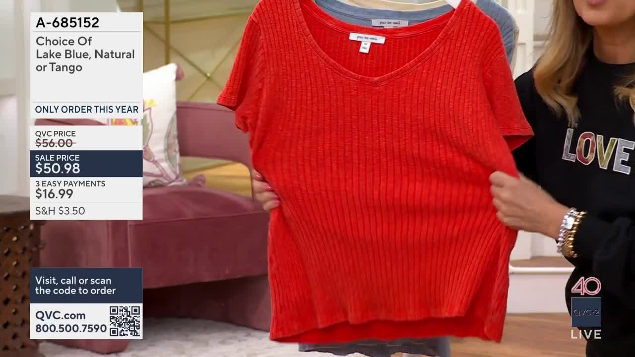 A vibrant red, ribbed top is held up, its fabric stretching slightly. Another woman stands nearby, wearing a black sweatshirt with "LOVE" emblazoned across it.