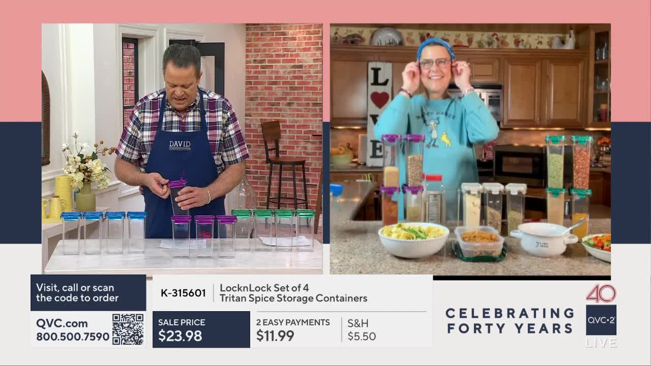 A man in an apron is demonstrating clear spice containers with purple lids. To his right, a woman in a blue sweatshirt smiles, holding her hands to her ears, surrounded by similar containers filled with spices.