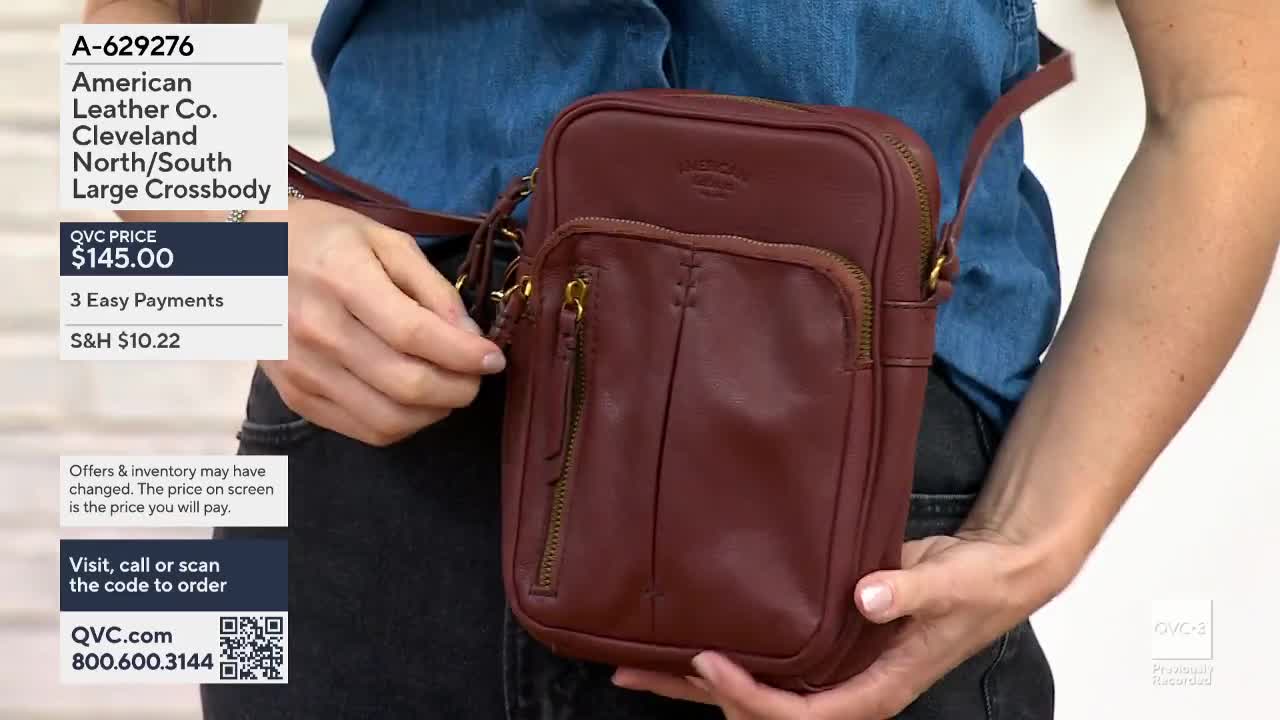 On QVC3, a person holds a burgundy crossbody bag from American Leather Co. in front of them, showing off the zipper detail. The price of the bag is displayed on the screen, along with the option for easy payments.
