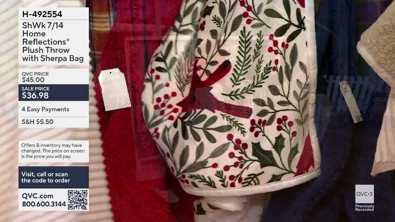 A plush throw with a holiday design is being displayed, its pattern of leaves and berries visible on QVC3. The price tag is attached to the side, and the sale price is clearly shown on the screen.
