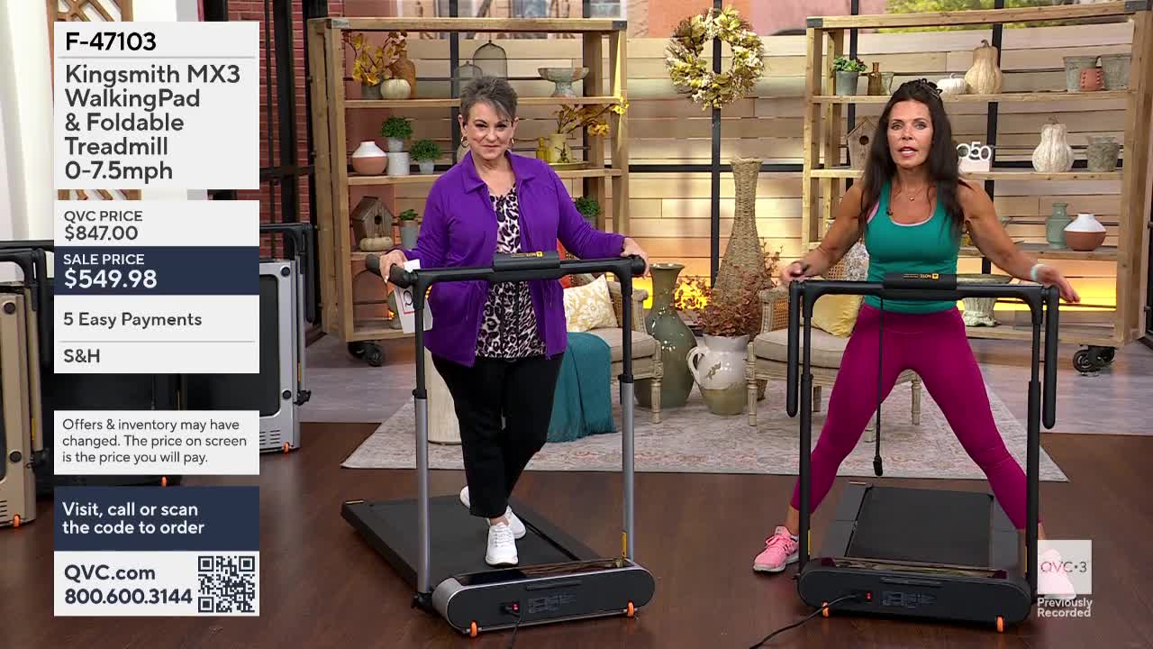 Two women on QVC3 are demonstrating treadmills. One woman walks slowly, while the other stands with her legs wide apart, holding the machine's handles.
