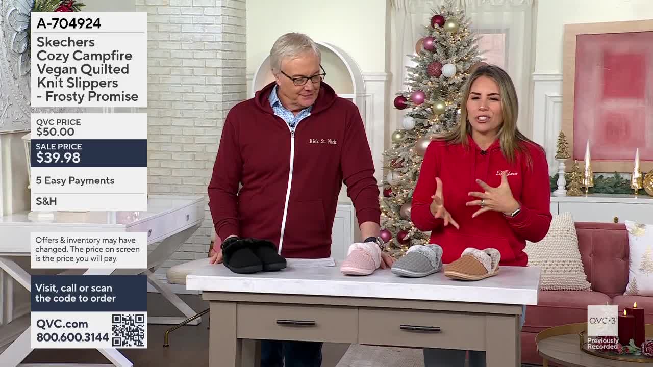 A woman in a red sweatshirt gestures towards the various colors of Skechers slippers displayed on a table. The man next to her, wearing a burgundy zip-up, glances at the footwear as well, all while a QVC3 graphic displays the price.

