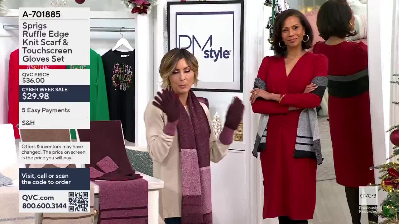 A woman in a cream sweater and a burgundy scarf and gloves gestures toward the camera on QVC3. Beside her, another woman in a red dress stands with her arms crossed.
