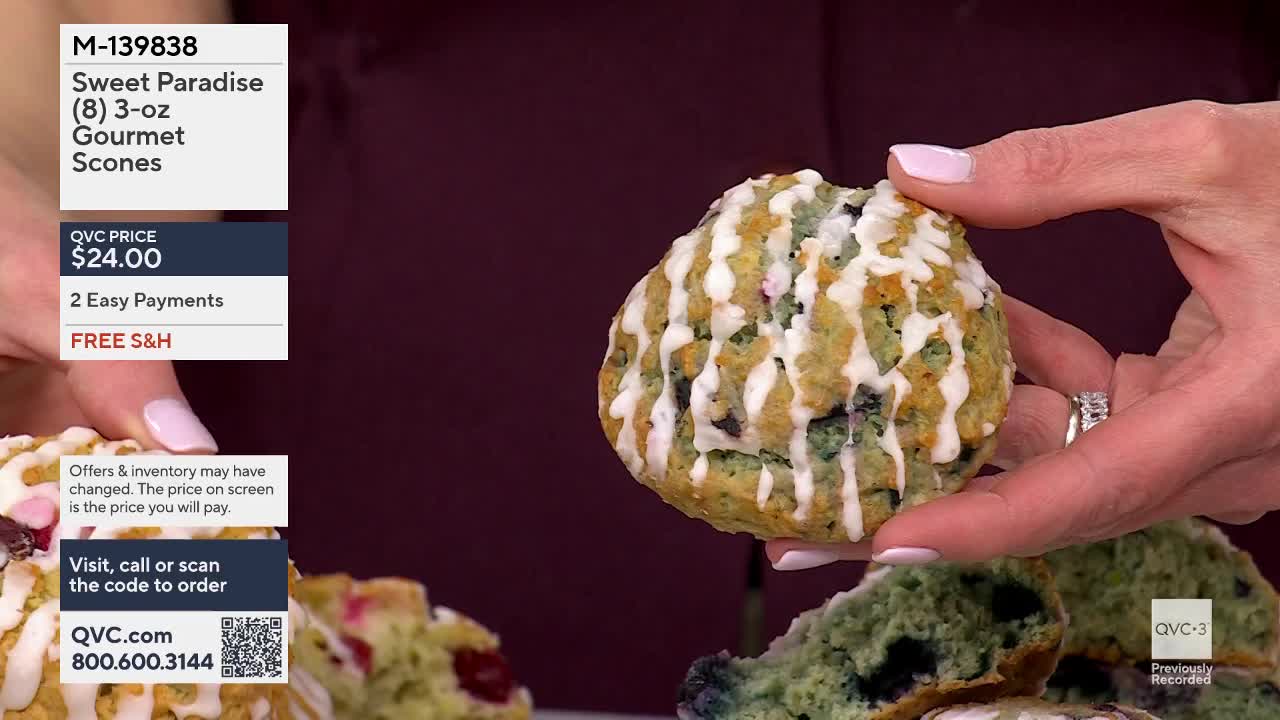 A hand holds up a blueberry scone, its white icing drizzled artfully. Another scone, cut in half, reveals its vibrant blue interior and scattered berries.