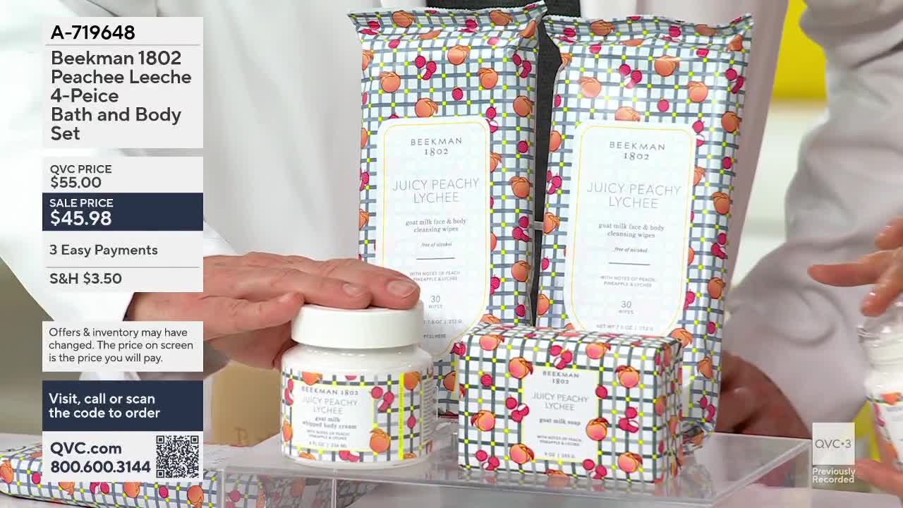 A hand reaches to adjust a jar of goat milk cream. Two packages of cleansing wipes and a box of soap sit behind it, all adorned with a peachy lychee pattern.