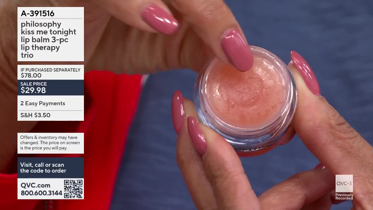 A finger dips into a small, clear jar of peachy-pink lip balm. The QVC logo appears in the corner of the screen.