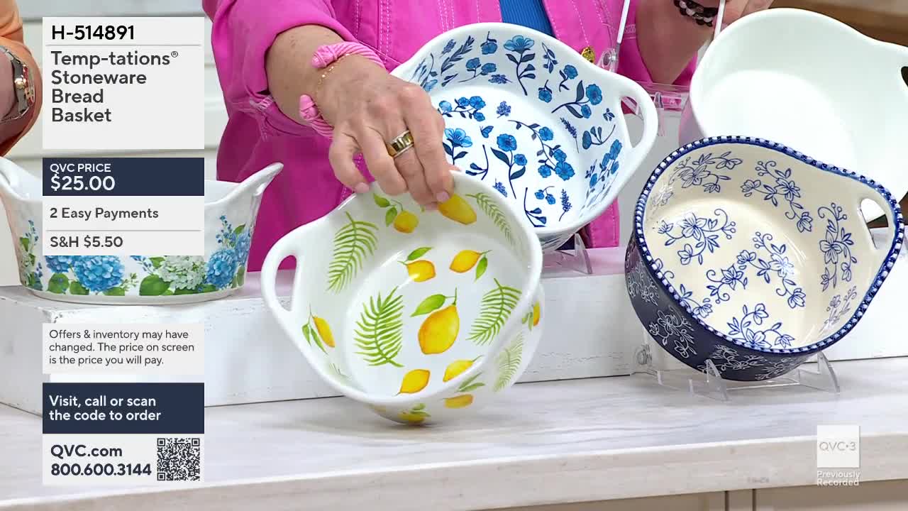A hand turns a white bread basket adorned with bright yellow lemons and green palm fronds. Another basket with blue floral designs sits behind it.