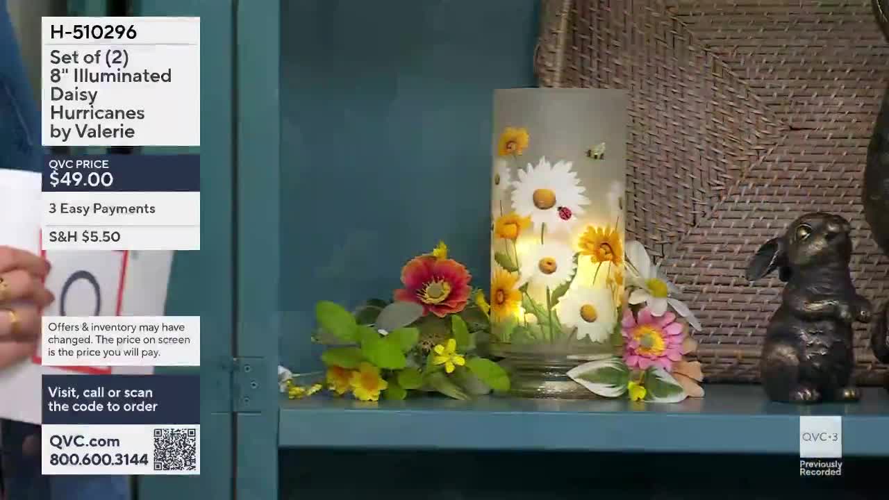 A glass hurricane lamp, painted with daisies and ladybugs, glows warmly. A small, dark bronze bunny figurine stands guard beside it.