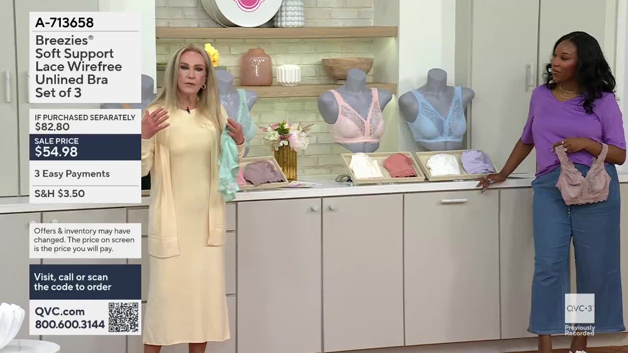 A woman in a pale yellow dress gestures with a light blue fabric. Beside her, a woman in a purple top holds up a delicate lace bra.