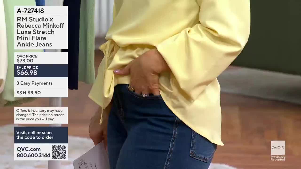 A hand slides into the pocket of dark wash jeans. The woman wears a bright yellow blouse with bell sleeves.